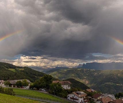 Gewitterwolken und ein Regenbogen über Jenesien