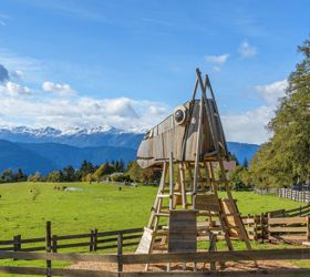 Large wooden playground structure shaped like a horse's head on a meadow with mountain views.