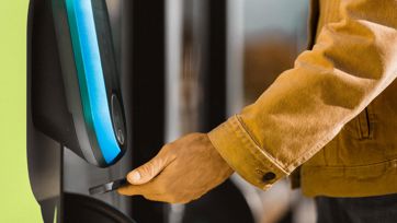 Fahrgast scannt Ticket mit Smartphone am grünen Fahrkartenleser an der Tür eines Busses.