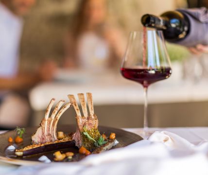 Fein angerichtetes Lammkarree mit Gemüse und Rotwein in elegantem Restaurantambiente